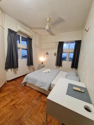 a bedroom with a bed and a desk and two windows at JJ Home 2 , Jalan Burmah, Georgetown in George Town