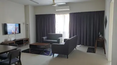 a living room with a couch and a chair and a television at TESS - By The Sea, Batu Ferringhi Penang in Batu Ferringhi