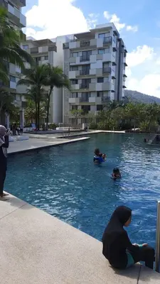 a person sitting in the water in a swimming pool at TESS - By The Sea, Batu Ferringhi Penang in Batu Ferringhi