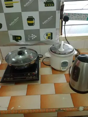 a kitchen counter with a stove with a pan and a pot at Irfans HomestayDouble storey in Seri Manjung