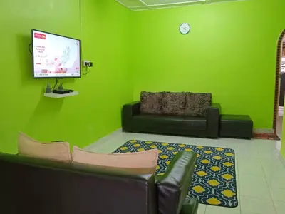 a green living room with a couch and a tv at Irfans HomestayDouble storey in Seri Manjung