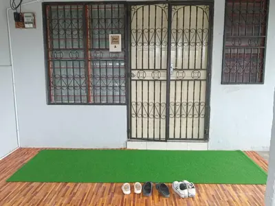 a pair of shoes on a green rug in front of a door at Irfans HomestayDouble storey in Seri Manjung