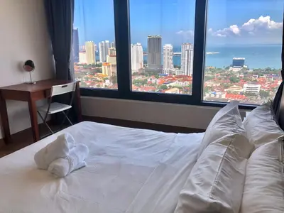 a bed in a bedroom with a view of a city at Tropicana 218 Macalister Water Purifier By Blue Sky Holidays in George Town