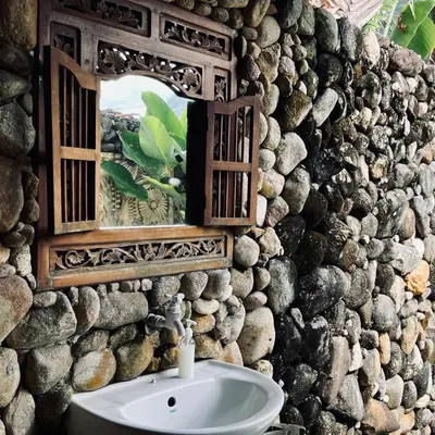 a bathroom with a stone wall with a sink and a mirror at Sahom Valley Resort - Agro & Eco Park in Kampar