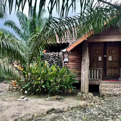 a wooden cabin with a bench and palm trees at Sahom Valley Resort - Agro & Eco Park in Kampar
