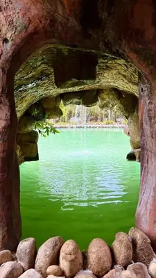 a view of a green lake through a stone window at Sahom Valley Resort - Agro & Eco Park in Kampar