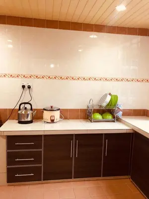 a kitchen with black cabinets and a counter top at BRINCHANG CENTRE 3 ROOMS APARTMENT in Cameron Highlands