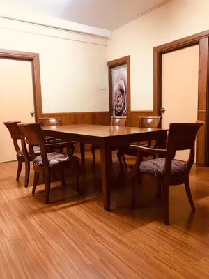 a dining room table with chairs and a picture on the wall at BRINCHANG CENTRE 3 ROOMS APARTMENT in Cameron Highlands