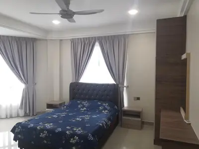 a bedroom with a bed with a blue comforter and a window at Orkid Apartment in Cameron Highlands