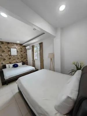 a bedroom with two beds and a stone wall at Cozy Suite for 2-6 pax near Kek Lok Si, Penang Hill, Sunshine Central in Ayer Itam
