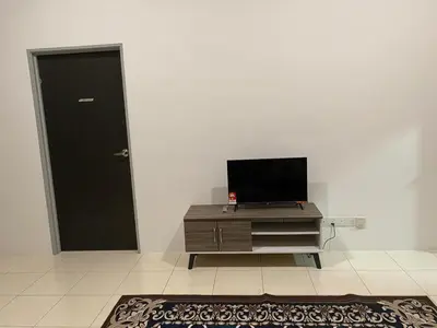 a living room with a television on a dresser and a door at An-Nur Homestay in Sungai Petani