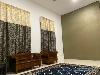 a living room with two chairs and curtains at An-Nur Homestay in Sungai Petani