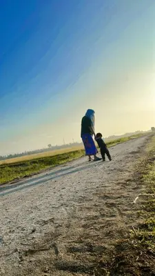 a woman and a dog walking down a road at Izz Homestay Sawah Padi Sungai Besar ! in Kampong Parit Ten