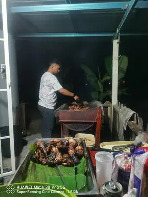 a man is cooking food on a grill at Izz Homestay Sawah Padi Sungai Besar ! in Kampong Parit Ten