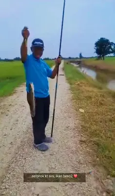 a man holding a pole on a dirt road at Izz Homestay Sawah Padi Sungai Besar ! in Kampong Parit Ten