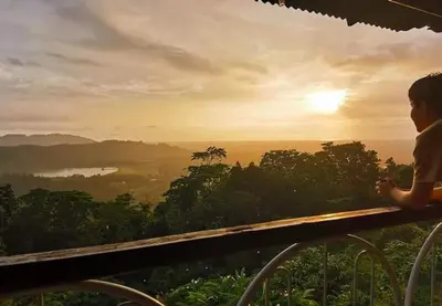 a person sitting on a fence watching the sunset at BUKIT LIMAU REST HOUSE in Taiping