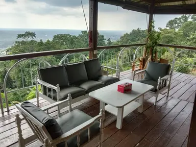 a porch with a couch and a table and chairs at BUKIT LIMAU REST HOUSE in Taiping