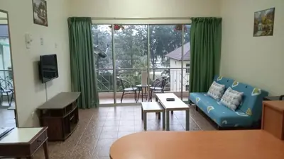 a living room with a blue couch and a balcony at Apartment Teluk Batik in Lumut