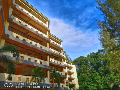 a large building with trees in the background at Apartment Teluk Batik in Lumut
