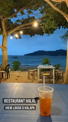 a drink sitting on a table in front of a beach at Pangkor Coralbay Resort Room 208 apartment in Pangkor