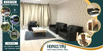 a living room with black couches and a table at Suria Permai Homestay in Taiping