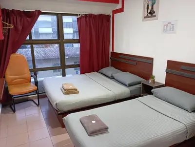 a bedroom with two beds and a chair and a window at Evonne Budget Hotel in Tanah Rata