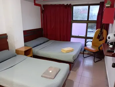 a room with two beds and a chair and a window at Evonne Budget Hotel in Tanah Rata
