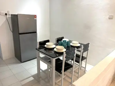 a kitchen with a table with chairs and a refrigerator at Entire Cozy Home 16 • 3 bedroom @ Alma Bukit Mertajam in Bukit Mertajam