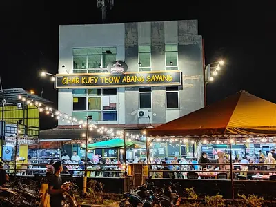 a building with people sitting at tables outside at night at Adelea Homestay MERU in Ipoh