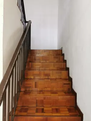 a staircase with wooden floors and a white wall at Chill and Traditional House in Bercham Ipoh in Ipoh