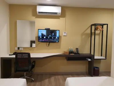 a room with a desk with a television on a wall at T SQUARE HOTEL (IPOH) in Ipoh