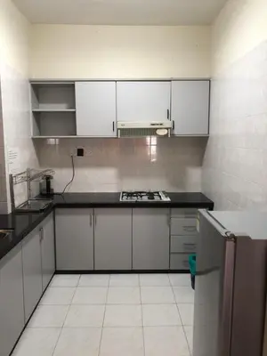 an empty kitchen with white cabinets and a stove at Beach Resort Home Stay SRI SAYANG APARTMENT BATU FERRINGHI 2BEDROOM in Batu Ferringhi