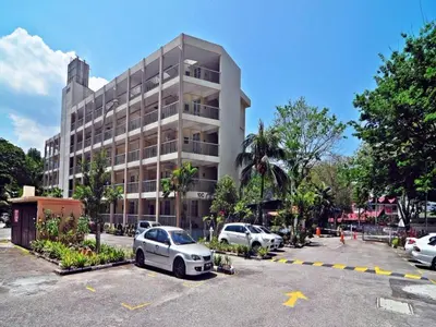 a white car parked in a parking lot in front of a building at Bayu Emas Apartment by Wellington Resorts in Batu Ferringhi