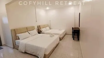 a room with two beds and a desk in it at CofyHill Retreat in Kampong Changkat Tualang