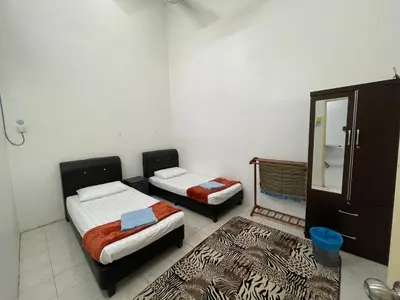 a room with two beds and a dresser and a mirror at Homestay Bidor DMaju in Bidur