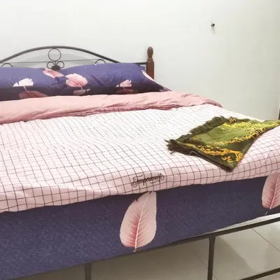 a bed with a pink and purple comforter at Homestay Inap Bakawali Seri Iskandar in Seri Iskandar