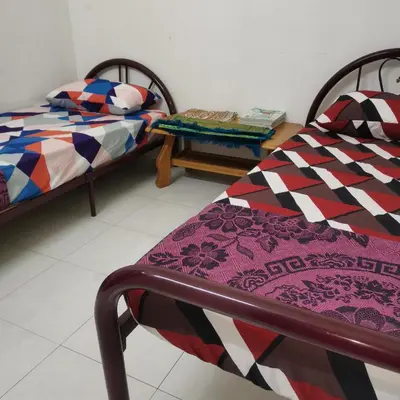 a room with two beds and a table in it at Homestay Inap Bakawali Seri Iskandar in Seri Iskandar