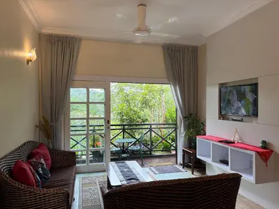 a living room with a couch and a balcony at Gerard's Place Nature Haven Apartment in Tanah Rata