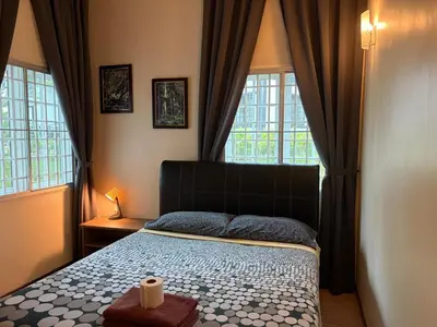 a bedroom with a bed and two large windows at Gerard's Place Nature Haven Apartment in Tanah Rata