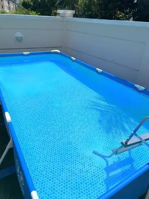 a blue swimming pool with a chair in it at FERRINGHI RESORT 5-BEDROOM with POOL, BBQ SET, WiFi, Netflix & WALK to BEACH in Batu Ferringhi