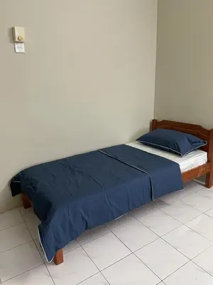 a bed in a bedroom with a blue comforter at To' Teh Homestay in Ipoh