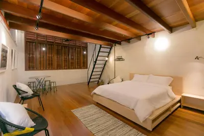 a bedroom with a bed and chairs and a staircase at Central Georgetown - Loft House in George Town