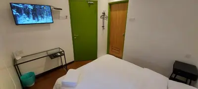 a small room with a bed and a green door at Olive Bedz Hotel in Tambun