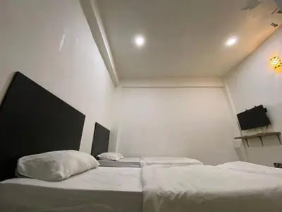 two beds in a room with white walls at Hotel station 24 in Sungai Besar