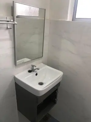 a white bathroom with a sink and a mirror at Hotel station 24 in Sungai Besar