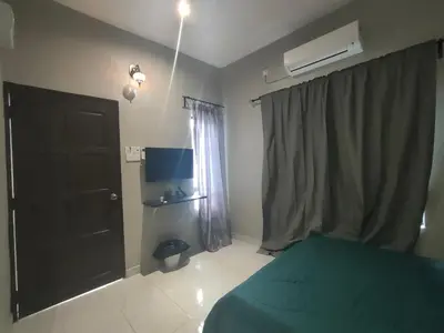 a bedroom with a green bed and a black door at MAMA homestay in Bagan Serai