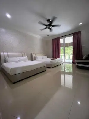 two beds in a bedroom with a ceiling fan at Homestay Seri Pangkor in Pangkor