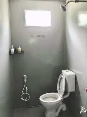 a bathroom with a white toilet and a window at Teratak Ar-Rayyan x Villa Abi in Batu Kurau