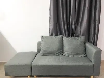 a gray couch with two pillows in front of a curtain at Teratak Ar-Rayyan x Villa Abi in Batu Kurau