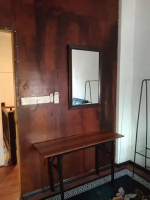 a mirror on a wall next to a wooden table at khairul homestay taman tengiri seberang jaya in Kampong Telok